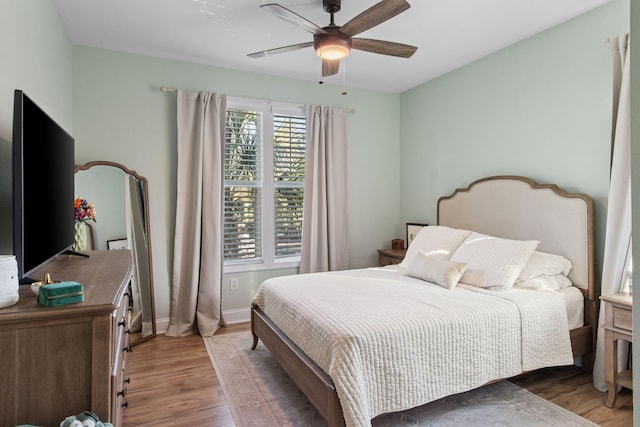 bedroom with light wood finished floors, baseboards, and a ceiling fan