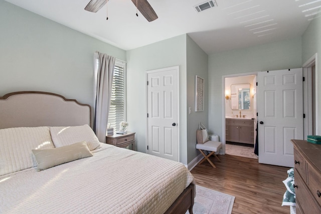 bedroom with visible vents, ensuite bathroom, ceiling fan, wood finished floors, and baseboards