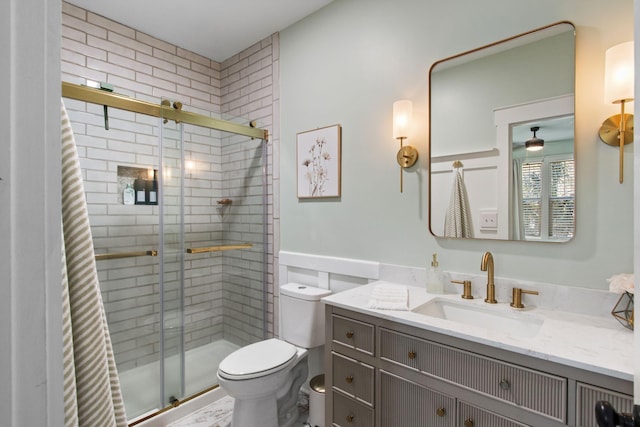 bathroom featuring a shower stall, toilet, and vanity