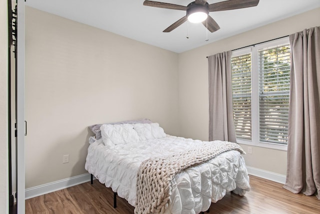 bedroom featuring ceiling fan, baseboards, and wood finished floors