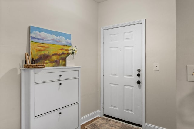 doorway featuring dark wood-style flooring and baseboards