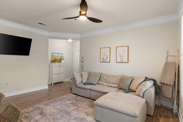 living room with visible vents, wood finished floors, and ornamental molding