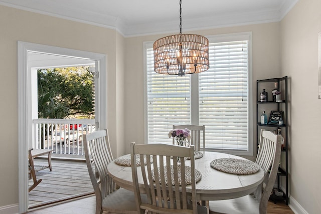 dining area featuring baseboards, ornamental molding, a notable chandelier, and wood finished floors