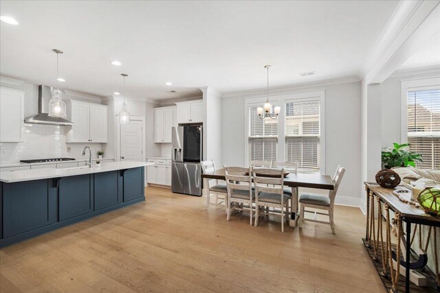 113 Grimball St, Summerville, SC 29486 - kitchen featuring stainless steel fridge, wall chimney exhaust hood, light wood-style floors, light countertops, and ornamental molding