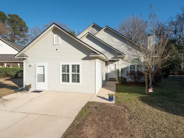 back of house featuring a patio, a lawn, and driveway