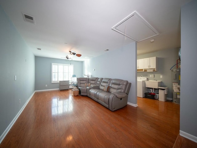 living room featuring visible vents, baseboards, attic access, washer / dryer, and wood finished floors