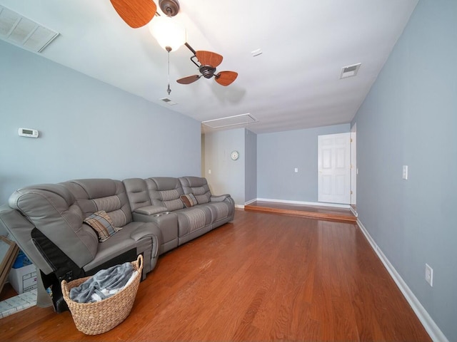 living room with visible vents, wood finished floors, and a ceiling fan