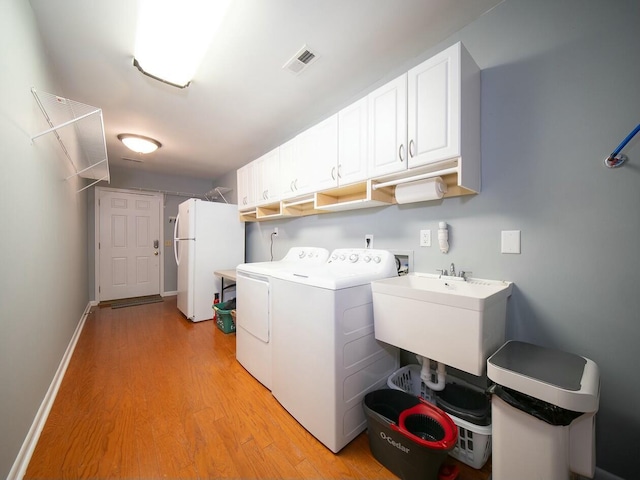 washroom with visible vents, light wood-style floors, cabinet space, independent washer and dryer, and a sink