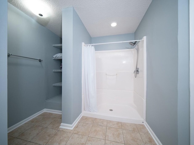 bathroom with tile patterned floors, a shower with curtain, baseboards, and a textured ceiling