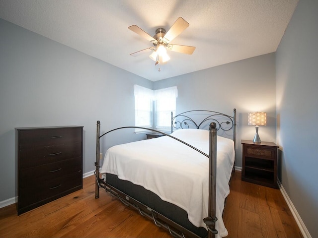 bedroom featuring ceiling fan, baseboards, a textured ceiling, and wood finished floors