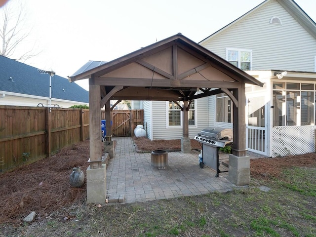 view of patio featuring a gazebo, area for grilling, a fenced backyard, and a sunroom