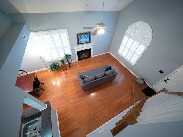 living room with baseboards, wood finished floors, a fireplace, and vaulted ceiling