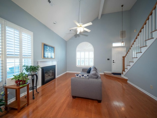 living area with visible vents, baseboards, stairs, wood finished floors, and a glass covered fireplace