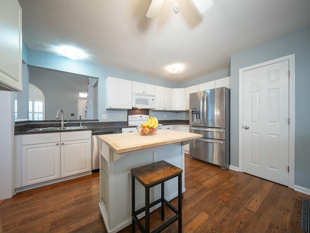 kitchen with butcher block countertops, a sink, a center island, stainless steel appliances, and white cabinets