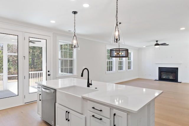 kitchen with sink, white cabinetry, hanging light fixtures, an island with sink, and stainless steel dishwasher