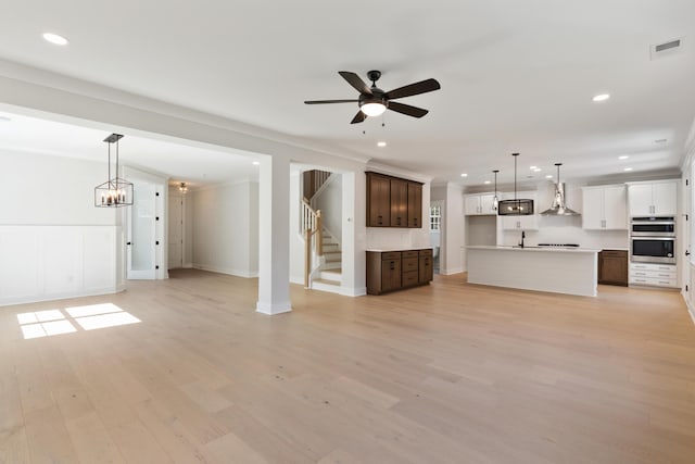 unfurnished living room featuring ceiling fan, ornamental molding, sink, and light hardwood / wood-style floors