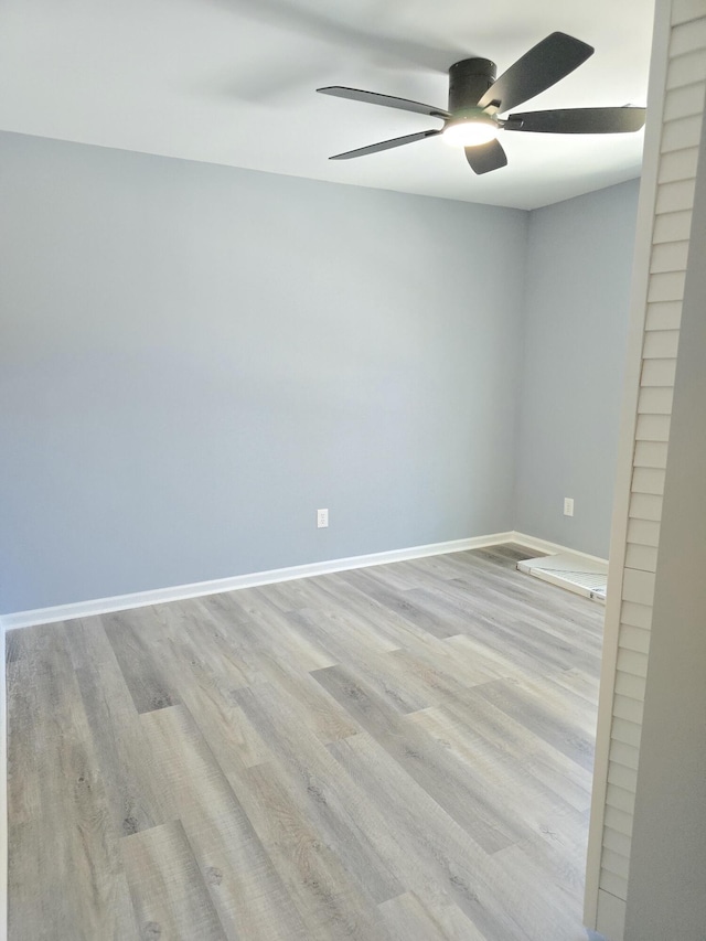 spare room with a ceiling fan, light wood-type flooring, and baseboards