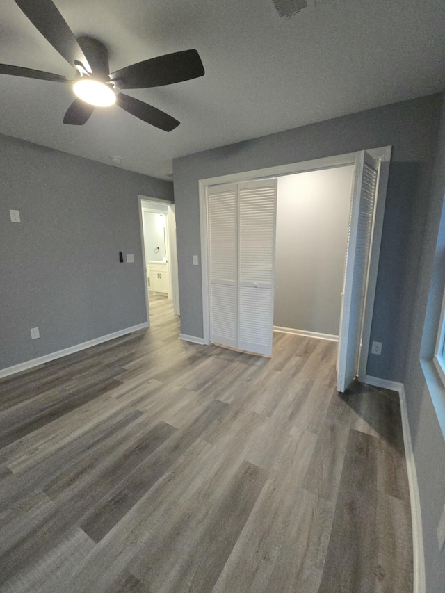 unfurnished bedroom with a closet, wood finished floors, a ceiling fan, and baseboards