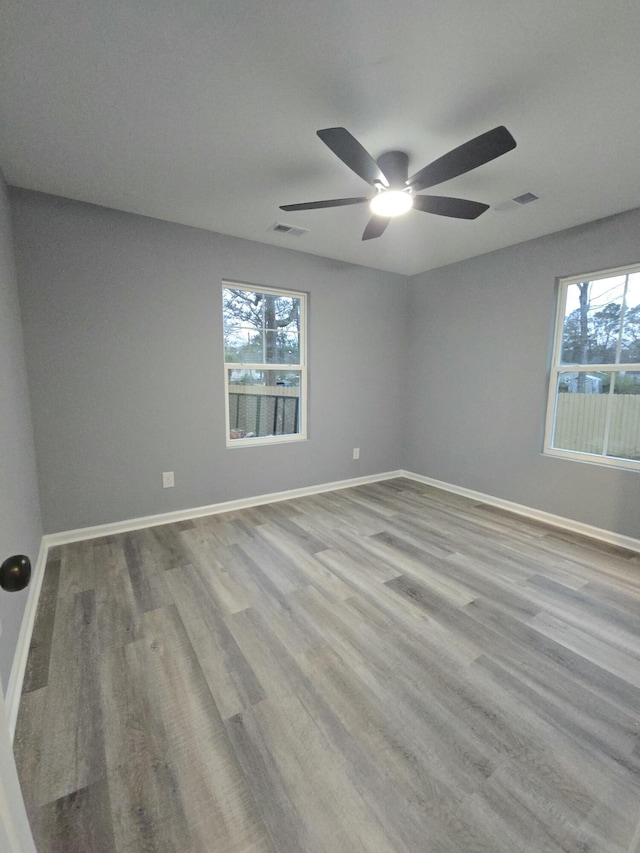 spare room with light wood-type flooring, visible vents, plenty of natural light, and baseboards