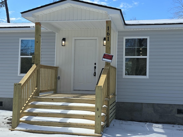 snow covered property entrance featuring crawl space