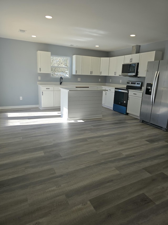 kitchen featuring dark wood finished floors, stainless steel appliances, light countertops, white cabinets, and a sink