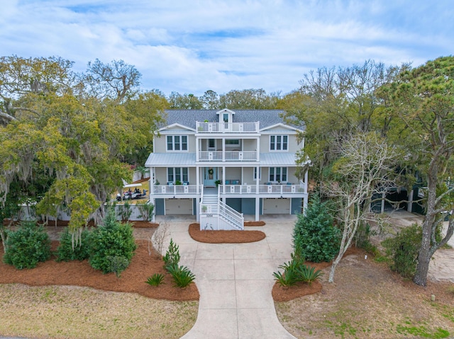 view of front of home with a porch, concrete driveway, a garage, a balcony, and stairs