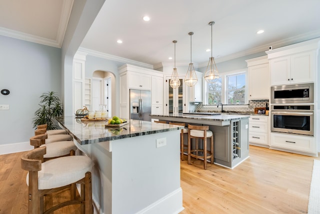 kitchen featuring backsplash, dark stone counters, a kitchen bar, light wood-style flooring, and stainless steel appliances