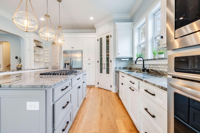 kitchen featuring light wood finished floors, open shelves, a sink, stainless steel appliances, and white cabinetry