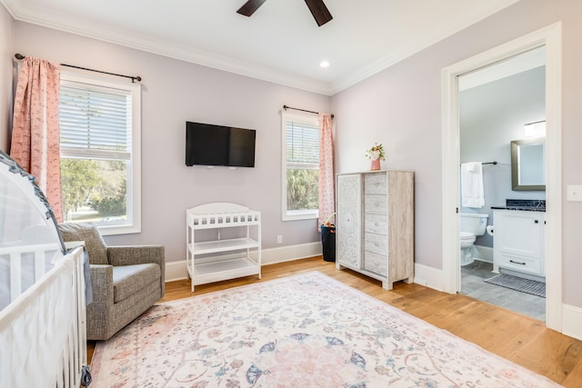 bedroom with ensuite bath, wood finished floors, crown molding, baseboards, and ceiling fan