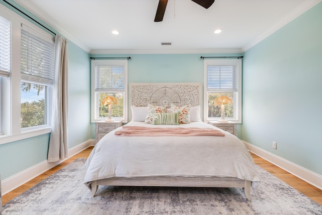 bedroom with light wood-style flooring, baseboards, visible vents, and ornamental molding