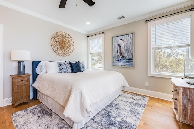 bedroom featuring visible vents, multiple windows, light wood-style flooring, and ornamental molding