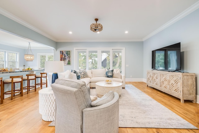 living area with plenty of natural light, light wood-style flooring, and ornamental molding