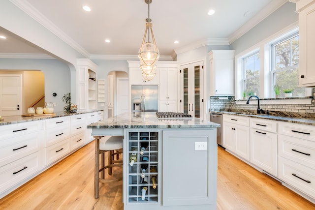 kitchen featuring open shelves, light wood-style floors, appliances with stainless steel finishes, and a sink