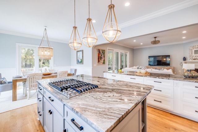 kitchen with light stone counters, open floor plan, a center island, and light wood-style floors