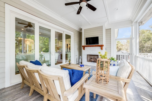 sunroom featuring exterior fireplace and a ceiling fan