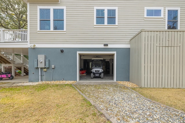 exterior space featuring stucco siding, a lawn, driveway, a garage, and stairs