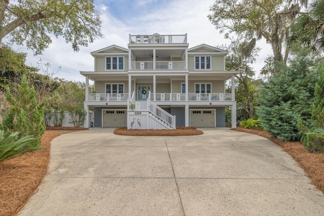 beach home with a balcony, a porch, stairs, concrete driveway, and a garage