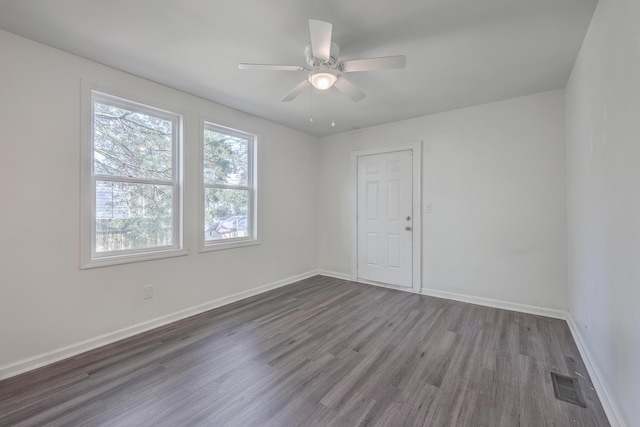 empty room featuring visible vents, ceiling fan, baseboards, and wood finished floors