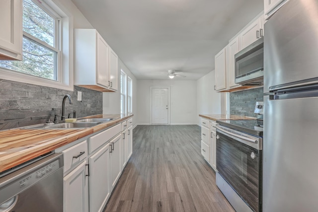 kitchen featuring light wood-type flooring, appliances with stainless steel finishes, white cabinets, and a sink