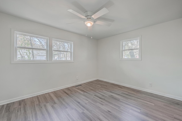 empty room featuring ceiling fan, wood finished floors, visible vents, and baseboards