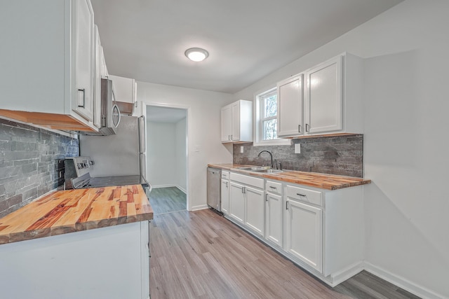 kitchen featuring a sink, stainless steel appliances, light wood-type flooring, and wood counters