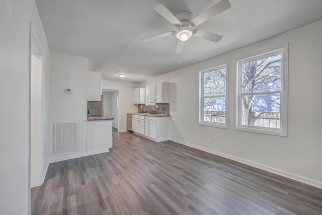 kitchen featuring visible vents, decorative backsplash, wood finished floors, freestanding refrigerator, and a sink