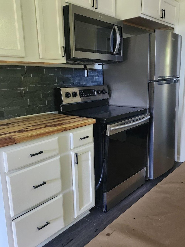 kitchen featuring white cabinetry, butcher block counters, appliances with stainless steel finishes, and decorative backsplash