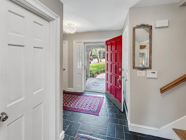 foyer entrance with stone tile floors and baseboards