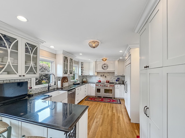 kitchen featuring appliances with stainless steel finishes, a peninsula, backsplash, and a sink