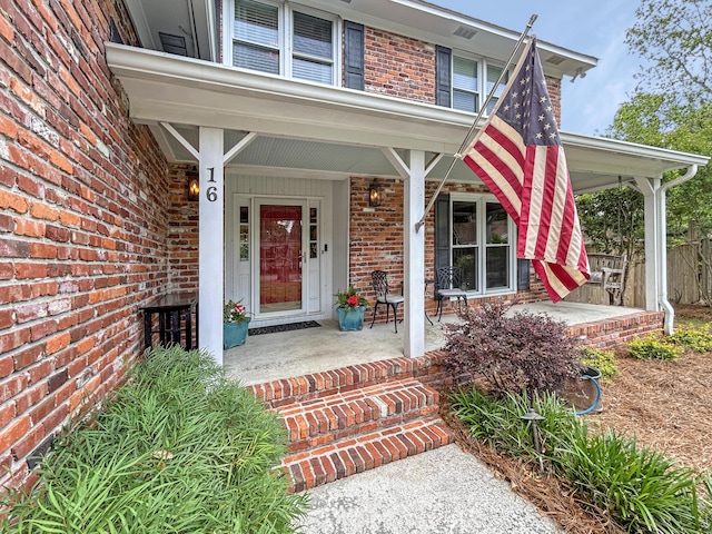 doorway to property with covered porch and brick siding