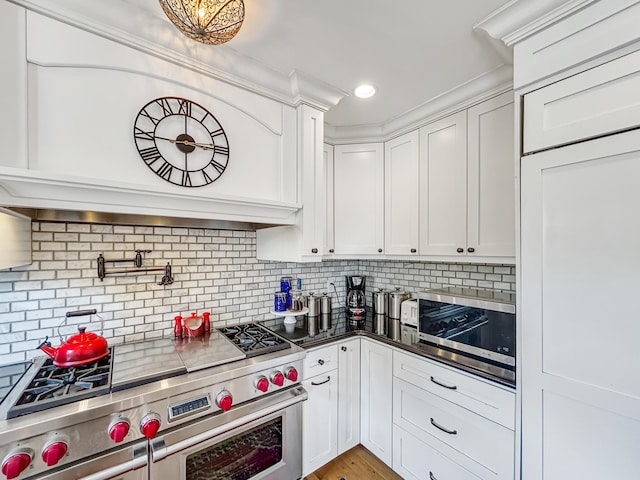 kitchen featuring recessed lighting, decorative backsplash, appliances with stainless steel finishes, white cabinets, and dark countertops