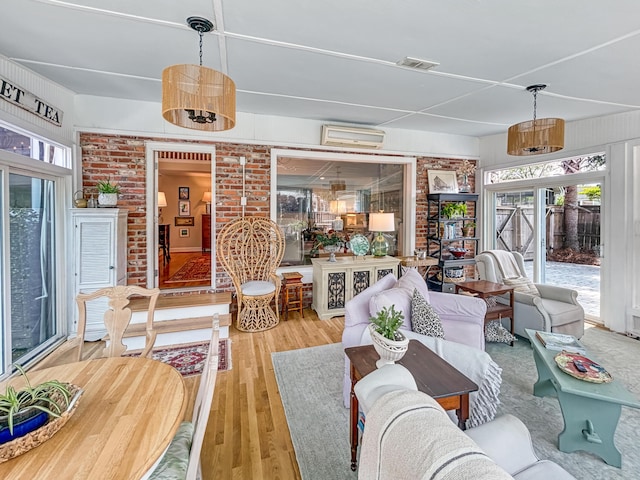 living room with visible vents, wood finished floors, and a wall mounted air conditioner