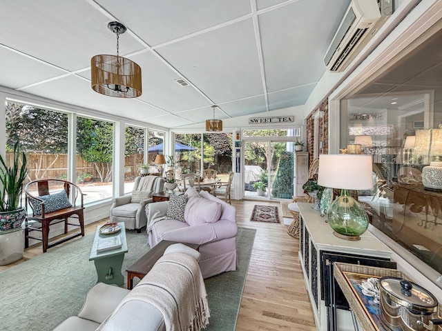 sunroom / solarium with wood finished floors, a healthy amount of sunlight, a wall mounted air conditioner, and visible vents