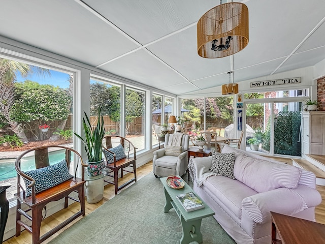 sunroom / solarium featuring wood finished floors, a wealth of natural light, and lofted ceiling